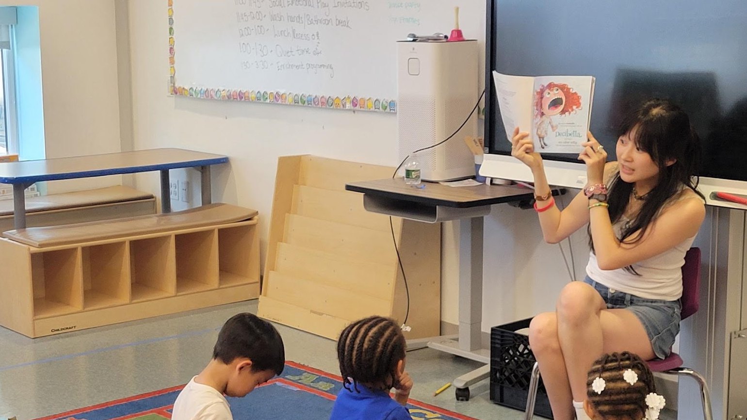 A Drexel education major reads a picture book to young children in a classroom.